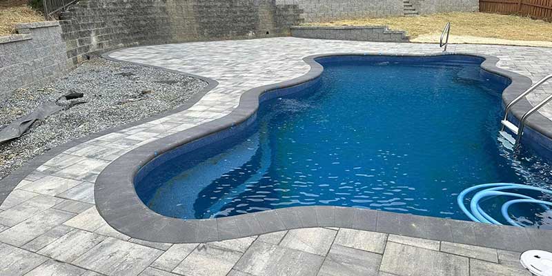 pool patio with stone and concrete blocks surrounding a pool in a residential property in Greensboro with retaining wall and concrete steps in the background pool patio with stone and concrete blocks surrounding a pool in a residential property in Greensboro with retaining wall and concrete steps in the background
