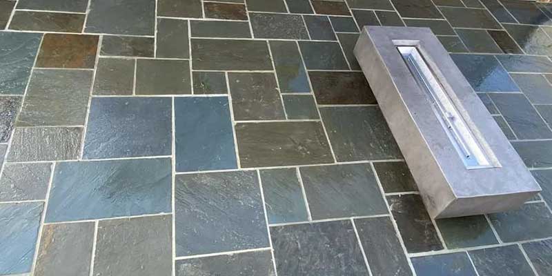 portion of a concrete driveway being refinished with concrete bricks, section surrounded by tools and foliage<br />

