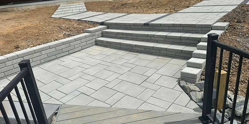 Stone walkway with stone steps leading to a decking with railing in a residential property in Kernersville, NC built by the santos hardscape team<br />